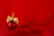 Luxury fashion red christmas ball with gold bow stand on deep silk red curtain with waves, copy space. New year background.