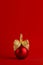 Luxury fashion red christmas ball with gold bow standing on deep silk red background, copy space, vertical. New year background.