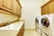 Luxury laundry room with wood cabinets and white machines.