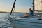 Luxury lifestyle. Side view of a relaxed senior man sitting on the side of sailboat or yacht floating in the calm blue