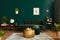 Luxury living room in house with modern interior design, green velvet sofa, coffee table, pouf, gold decoration, plant, commode.