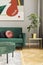 Luxury and modern home interior with design green sofa, navy commode, furniture and accessories. Abstract painting. Stylish home.