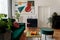 Luxury and modern home interior with design green sofa, navy commode, furniture and accessories. Abstract painting. Stylish home.