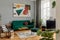 Luxury and modern home interior with design green sofa, navy commode, furniture and accessories. Abstract painting. Stylish home.