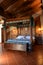 Luxury mountain hotel interior design. Sleeping room wooden canopy bed