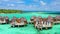 Luxury overwater villas with coconut palm trees, blue lagoon, white sandy beach at Bora Bora island, Tahiti, French