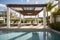 luxury pergola with sun loungers and parasols, surrounded by sparkling swimming pool