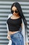 Luxury pretty modern young hipster woman in a summer cape in a black top in jeans with long black hair in stylish sunglasses