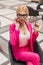 Luxury pretty young business woman in luxurious fashionable pink suit straightens stylish glasses. Beautiful modern glamorous girl