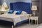 Luxury royal bedroom in antique style with blue velvet bed and white nightstand