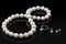 Luxury set white pearl necklace and jewelry with diamonds in ring and earrings on a black background