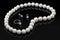 Luxury set white pearl necklace and jewelry with diamonds in ring and earrings on a black background with glossy reflection