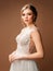 Luxury shiny lace wedding dress. Summer sleeveless bridal gown with tulle skirt and deep decollete. Attractive lady bride posing i