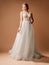 Luxury shiny lace wedding dress. Summer sleeveless bridal gown with tulle skirt and deep decollete. Happy lady bride posing in stu