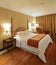 Luxury Spacious Bedroom with wooden flooring and gold coloured curtain