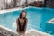 Luxury travel bikini girl with sexy body in black swimwear posing by swimming pool at luxurious villa. High fashion colors,