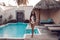 Luxury travel bikini girl with sexy body in white swimwear posing by swimming pool at luxurious villa. High fashion colors,