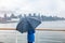 Luxury travel cruise woman leaving port watching city skyline of Vancouver under the rain with umbrella. Ship voyage destination
