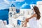 Luxury travel Greece vacation Asian elegant woman on honeymoon enjoying view of blue sea and three domes in white dress