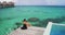 Luxury Travel Vacation on Bora Bora. Elegant woman in black dress relaxing enjoying view of coral reefs in French