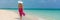 Luxury travel vacation elegant lady walking on beach in pink fashion skirt wrap relaxing on Caribbean holidays during