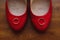 Luxury wedding rings on stylish red shoes of a bride on wooden b