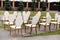 Luxury white-golden chairs on wedding ceremony outdoors. Festive decorations. Empty rows armchairs for guests. Outgoing