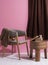 Luxury wooden chair with polished wooden table with three legs with pink wall with curtain in dark cafe in male space with books a