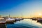 Luxury yachts, sailing and motor boats docked in sea port at sunset. Marine parking of modern motorboats, blue water. Travel.