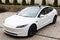 Lviv, Ukraine - March 23, 2024: White Tesla Model 3 highland electric car in showroom, trends in use EV in contemporary