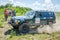 LVIV, UKRAINE - MAY 2016: Huge tuned car Jeep SUV driving on a dirt road rally, raising a cloud of dust behind, among the