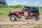 LVIV, UKRAINE - MAY 2016: Huge tuned car Jeep SUV driving on a dirt road rally, raising a cloud of dust behind, among the