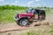 LVIV, UKRAINE - MAY 2016: Huge tuned car Jeep SUV driving on a dirt road rally, raising a cloud of dust behind, among the