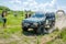 LVIV, UKRAINE - MAY 2016: Huge tuned car Jeep SUV driving on a dirt road rally, raising a cloud of dust behind, among the