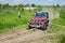 LVIV, UKRAINE - MAY 2016: Huge tuned car Jeep SUV driving on a dirt road rally, raising a cloud of dust behind, among the