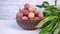 Lychee in bowl with leafs on wooden background