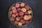 Lychees fruits in round bamboo bowl on black stone background surface with copy space