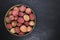 Lychees fruits in round bamboo bowl on black stone background surface with copy space