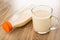 Lying bottle with milk, transparent cup  with baked milk on table