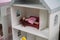 Lying in her miniature home, the doll represents the timeless nature of imaginative play, inviting viewers to reminisce