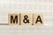 M&A abbreviation - mergers and acquisitions, on wooden cubes on a light background