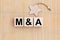 M and A - Merger and Acquisition - word wooden cubes