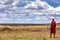 A Maasai tribesman walking through the grasslands of the Masai Mara, Kenya