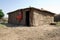 Maasai warrior leaning against his mud build hut.