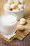 Macadamia milk in a glass and a bowl of macadamia nuts on a wooden background