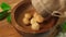 Macadamia nuts fall into wooden wood bowl on board. Close up.