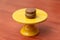 A macaron on a yellow stand on a table