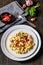 macaroni and cheese with corn, bacon topped with panko breadcrumbs on plates on dark wooden table