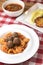 Macaroni dinner with meatballs. Meat pasta served in a white plate over red plaid tablecloth