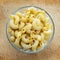 Macaroni Glass bowl with pasta on a wooden table. Close-up view from the top.